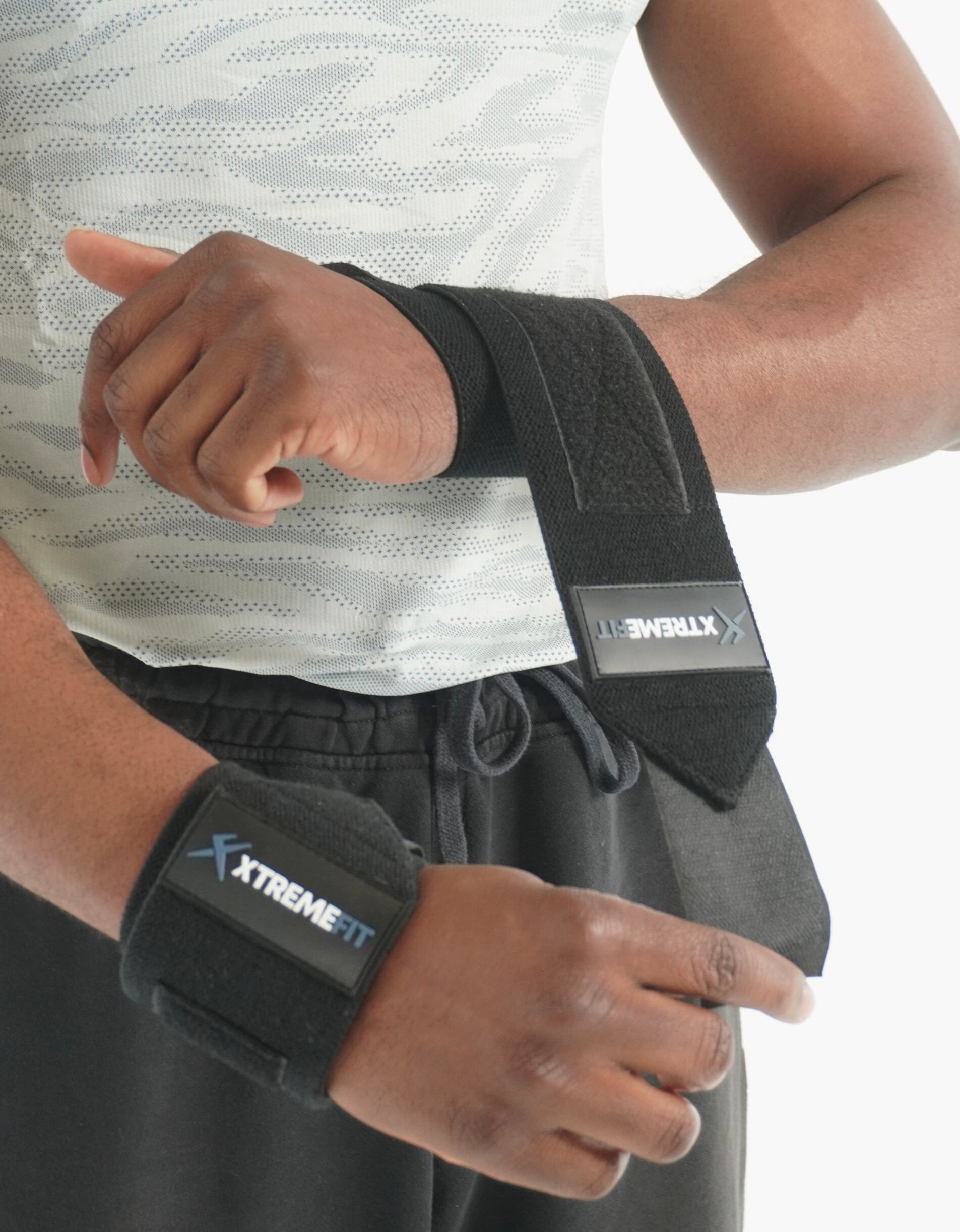 Athlète qui met les bandes de protections de poignets xtremefit noir pour la musculation et le powerlifting