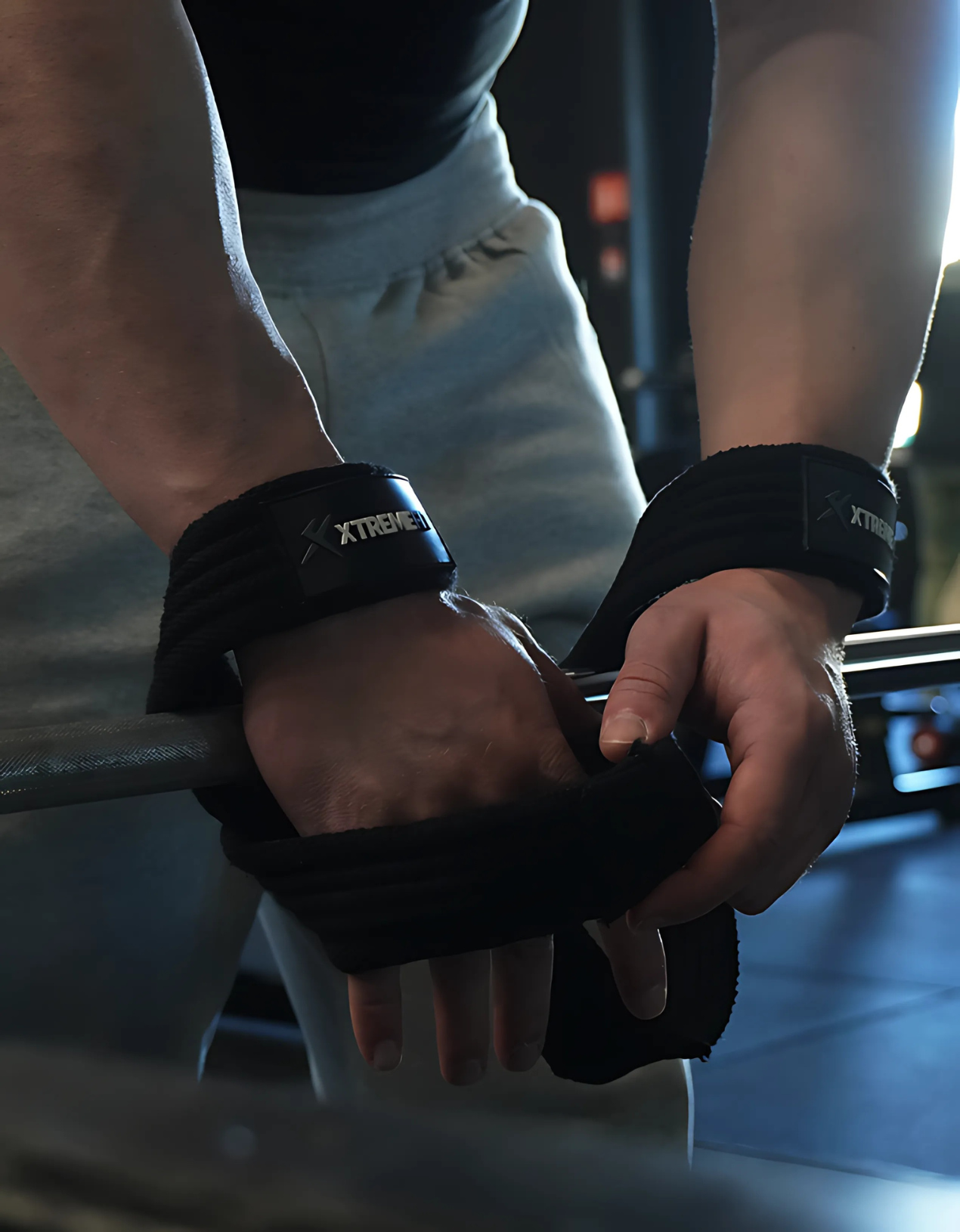Athlète mettant les sangles de levages en forme de 8 xtremefit noir en coton renforcé idéal pour le levage de charge et soulager le grip lors des exercices de bodybuilding, powerlifting ou muscu